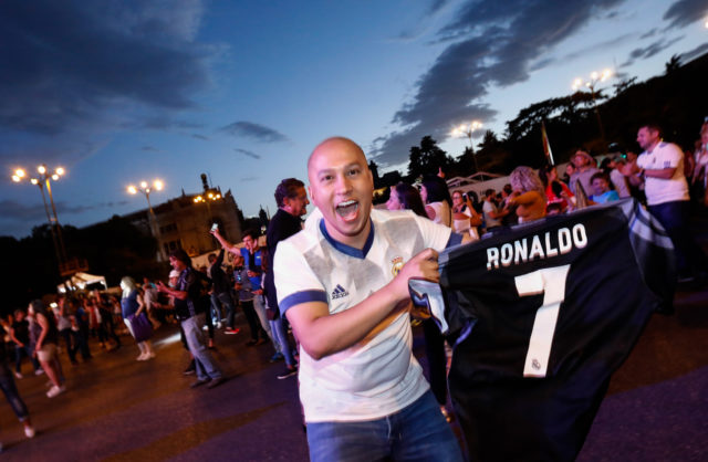 A Real Madrid football team fan shows a jersey with the name of Real Madrid's Portuguese forward Cristiano Ronaldo as he celebrates the team's win on Plaza Cibeles in Madrid on May 22, 2017 after the Spanish league football match Malaga CF vs Real Madrid CF held at La Rosaleda stadium in Malaga on May 21, 2017. Madrid sealed a first La Liga title in five years on May 21, 2017 -- and 33rd in total -- with a 2-0 victory at Malaga to bring a halt to Barcelona's domination of domestic matters having won six of the previous eight titles.