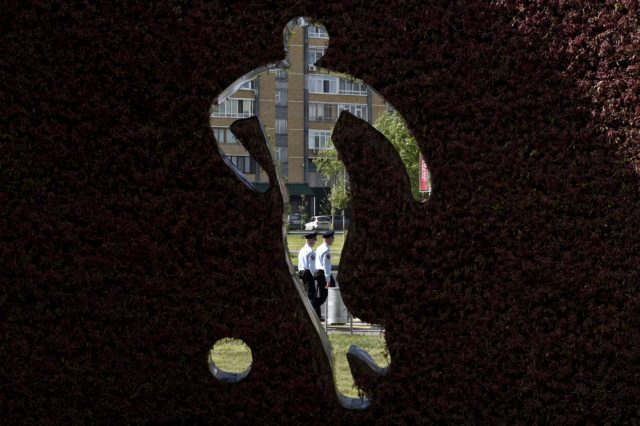 Police officers walk behind an artwork featuring a footballer outside the Kazan Arena stadium in Kazan, Russia, on June 17, 2017 on the eve of the Russia 2017 Confederations Cup football match Portugal vs Mexico.