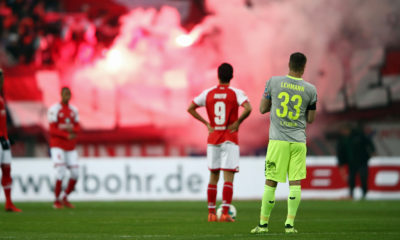 MAINZ, GERMANY - NOVEMBER 18: Yoshinori Muto #9 of Mainz and Matthias Lehmann of Koeln react as fans of Koeln burn flares during the Bundesliga match between 1. FSV Mainz 05 and 1. FC Koeln at Opel Arena on November 18, 2017 in Mainz, Germany. (Photo by Alex Grimm/Bongarts/Getty Images)