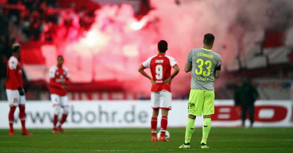 MAINZ, GERMANY - NOVEMBER 18: Yoshinori Muto #9 of Mainz and Matthias Lehmann of Koeln react as fans of Koeln burn flares during the Bundesliga match between 1. FSV Mainz 05 and 1. FC Koeln at Opel Arena on November 18, 2017 in Mainz, Germany. (Photo by Alex Grimm/Bongarts/Getty Images)