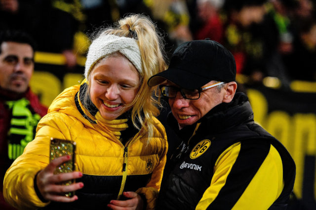 Dortmund's head coach Peter Stoeger (R) poses for a selfie photo with a fan prior to the German first division Bundesliga football match BVB Borussia Dortmund vs VfL Wolfsburg, in Dortmund, western Germany, on January 14, 2018. 