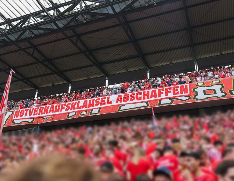 "Notverkaufsklausel abschaffen" steht auf dem Banner, das im Oberrang der Südkurve hängt. Im vorderen Bildbereich sind Fußballfans im Stehplatzbereich der Südkurve zu sehen.